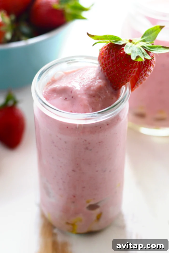 Thick Strawberry Pineapple Smoothie with fresh strawberry on the rim of the glass