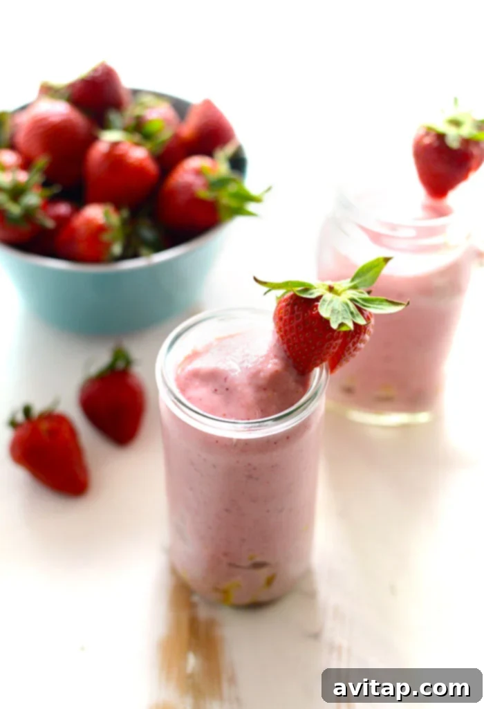 Strawberry pineapple smoothie in a bowl with pineapple chunks and whole strawberries as garnish