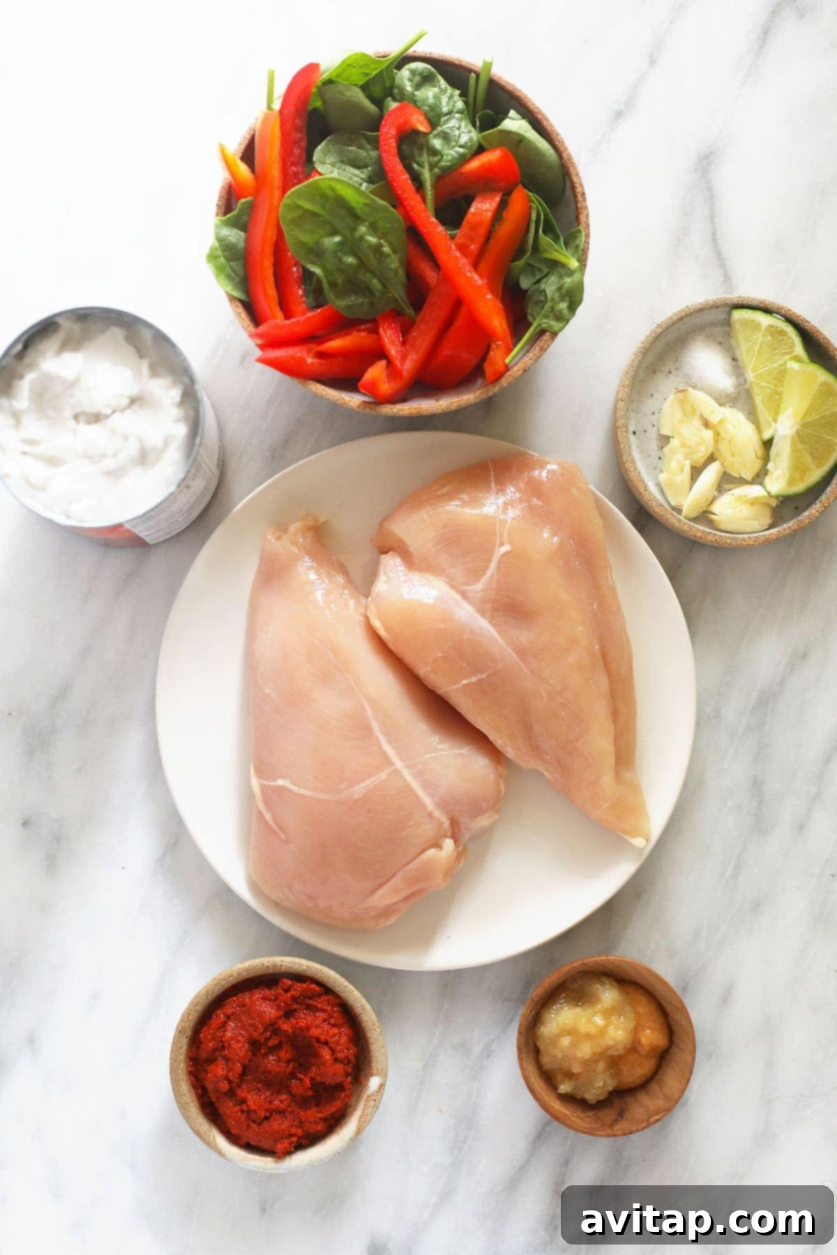 Fresh ingredients laid out for Instant Pot coconut curry chicken, including chicken breast, various vegetables, and flavor enhancers.
