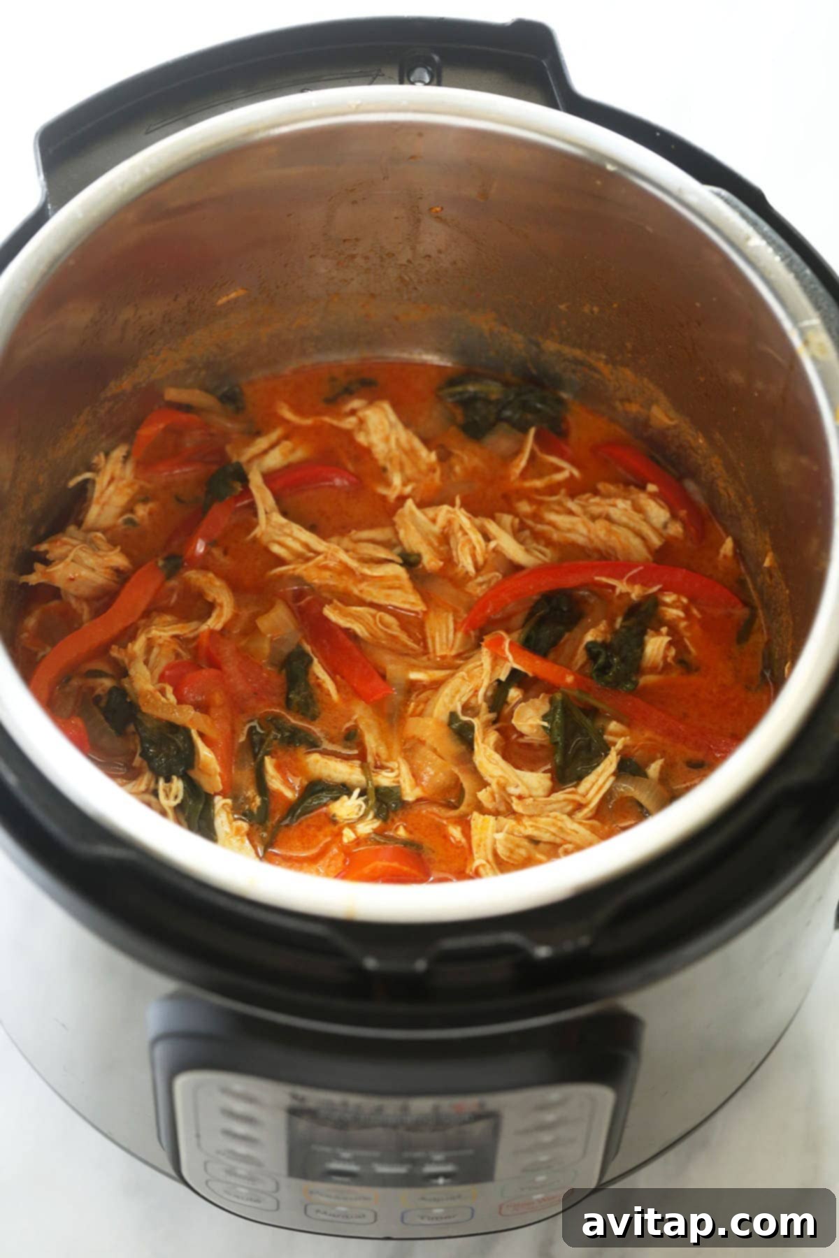 A top-down view of vibrant coconut curry chicken in an Instant Pot, garnished and ready to be served.