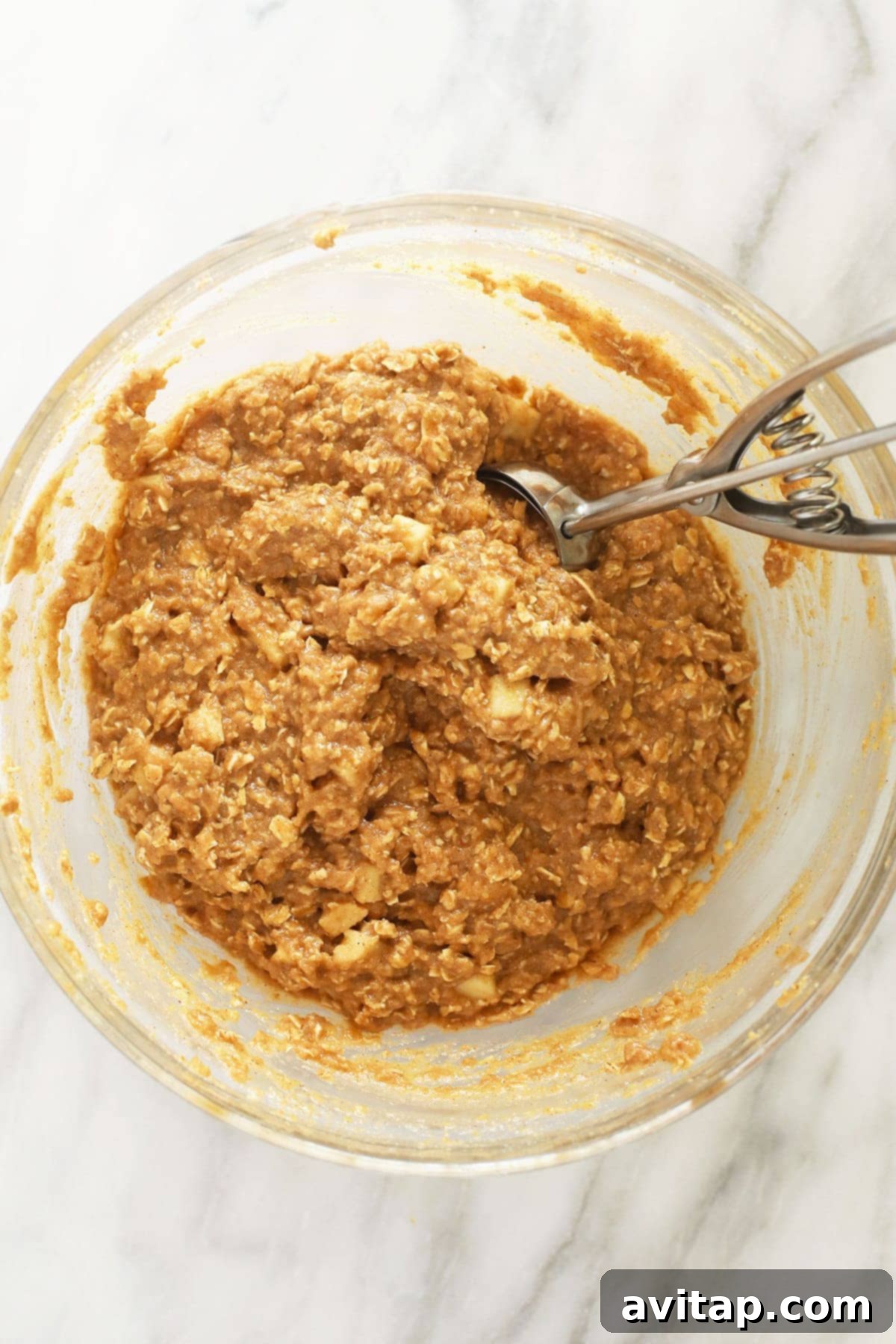 Apple oatmeal cookie batter in a mixing bowl, ready for scooping.