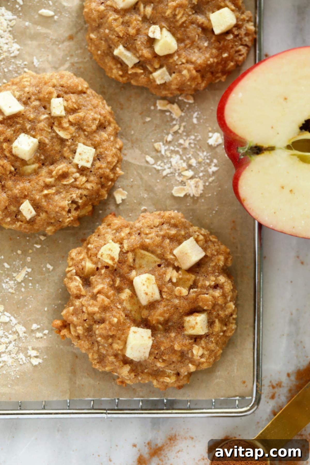 Freshly baked apple oatmeal cookies on a cooling rack, lightly dusted with cinnamon.