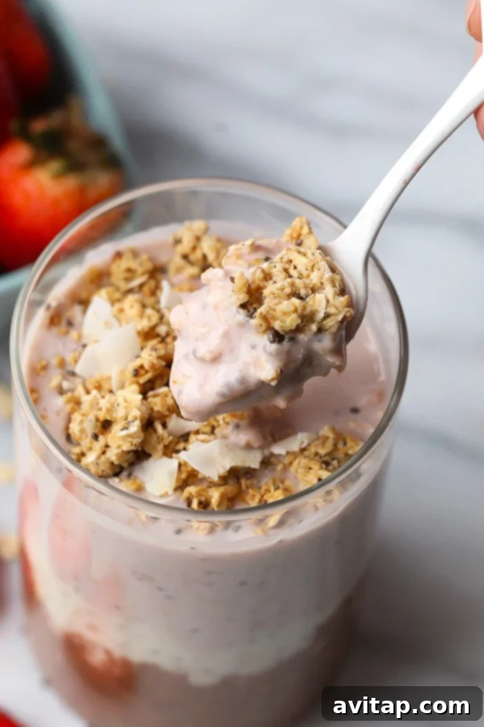 Neapolitan overnight oats served in a glass jar, with a spoonful perfectly poised and ready to eat, beautifully illustrating the creamy texture and inviting layered flavors.