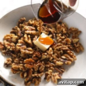 A person pouring maple syrup over walnuts and butter in a pan, initiating the candying process.