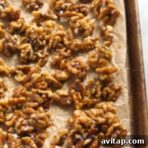 Candied walnuts spread out on parchment paper, seasoned with salt, and cooling for a Thanksgiving salad.