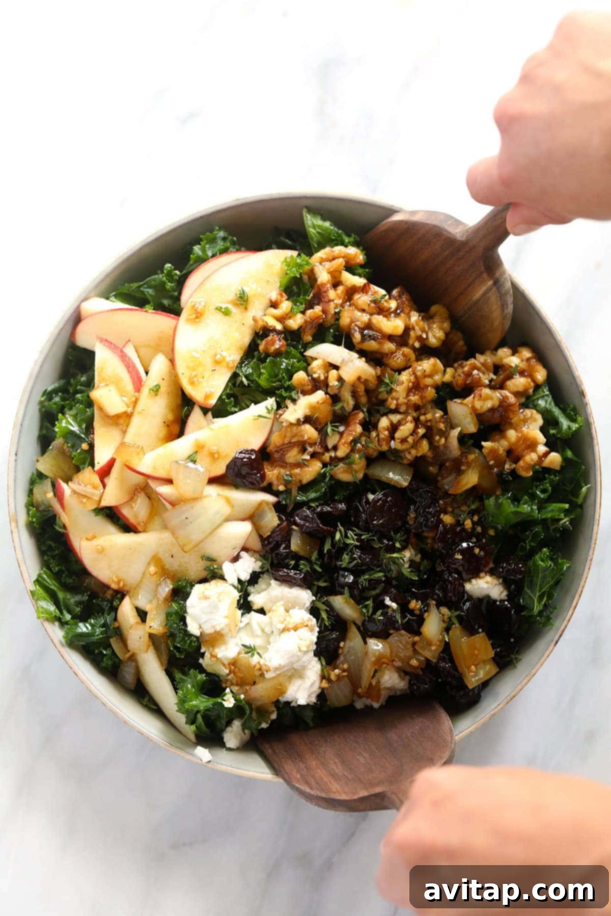 Our favorite Thanksgiving Salad recipe made with a massage kale salad base, apple slices, goat cheese, candied walnuts, and dried cherries! A vibrant Thanksgiving salad in a large wooden bowl, showcasing massaged kale, apple slices, dried cherries, and candied walnuts.