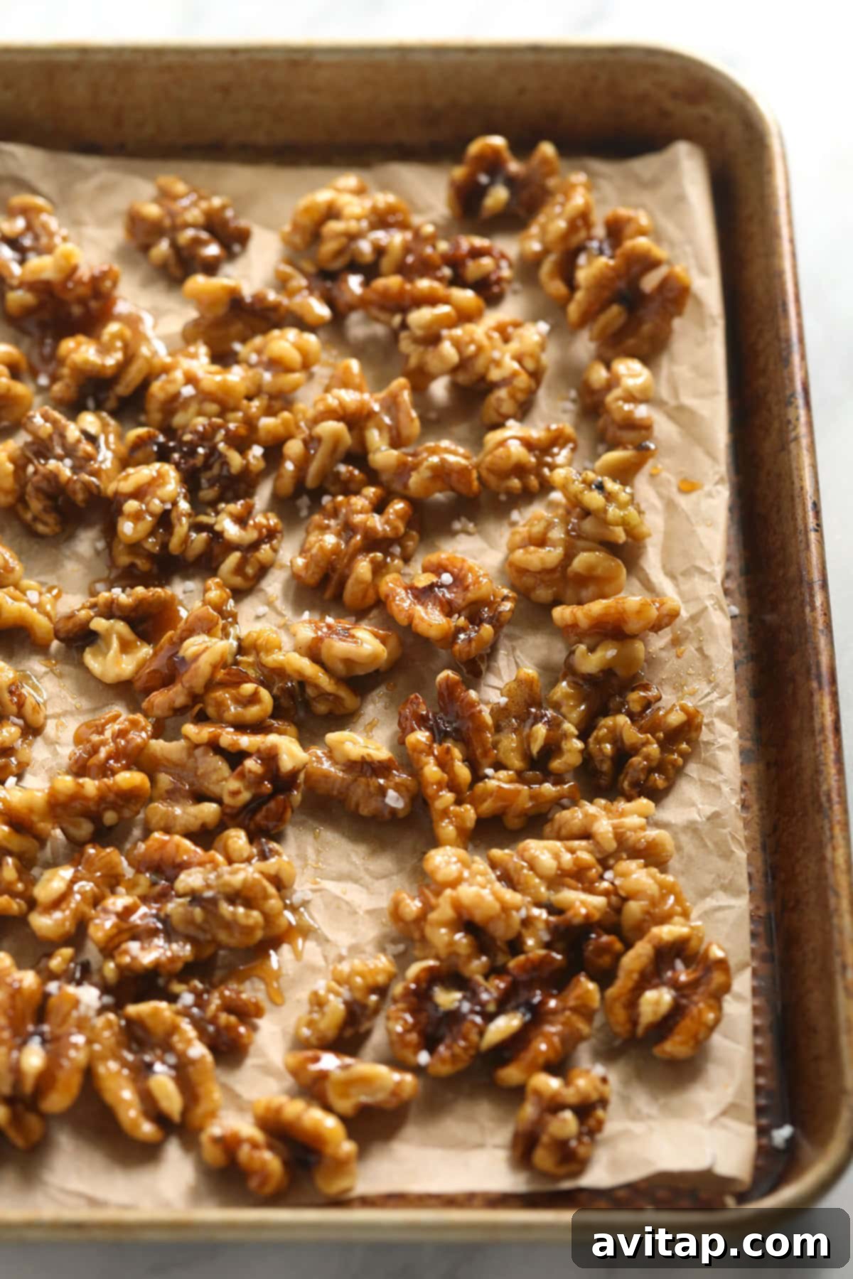 Looking for a last-minute Thanksgiving salad idea? Try our delicious massaged kale, apple, and walnut salad made with goat cheese, dried cherries, and our favorite vinaigrette! Freshly made candied walnuts cooling on a sheet pan, ready to be added to a Thanksgiving salad.