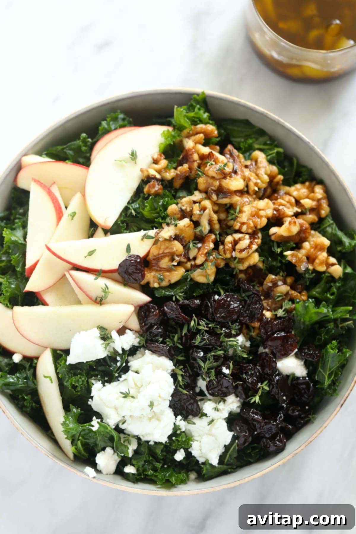 This flavorful Thanksgiving salad is made with massaged kale, sliced apple, candied walnuts, and goat cheese for a healthy side dish to share. A festive Thanksgiving salad elegantly arranged in a bowl, featuring tender kale, bright apple slices, and crunchy walnuts, ready to be served.
