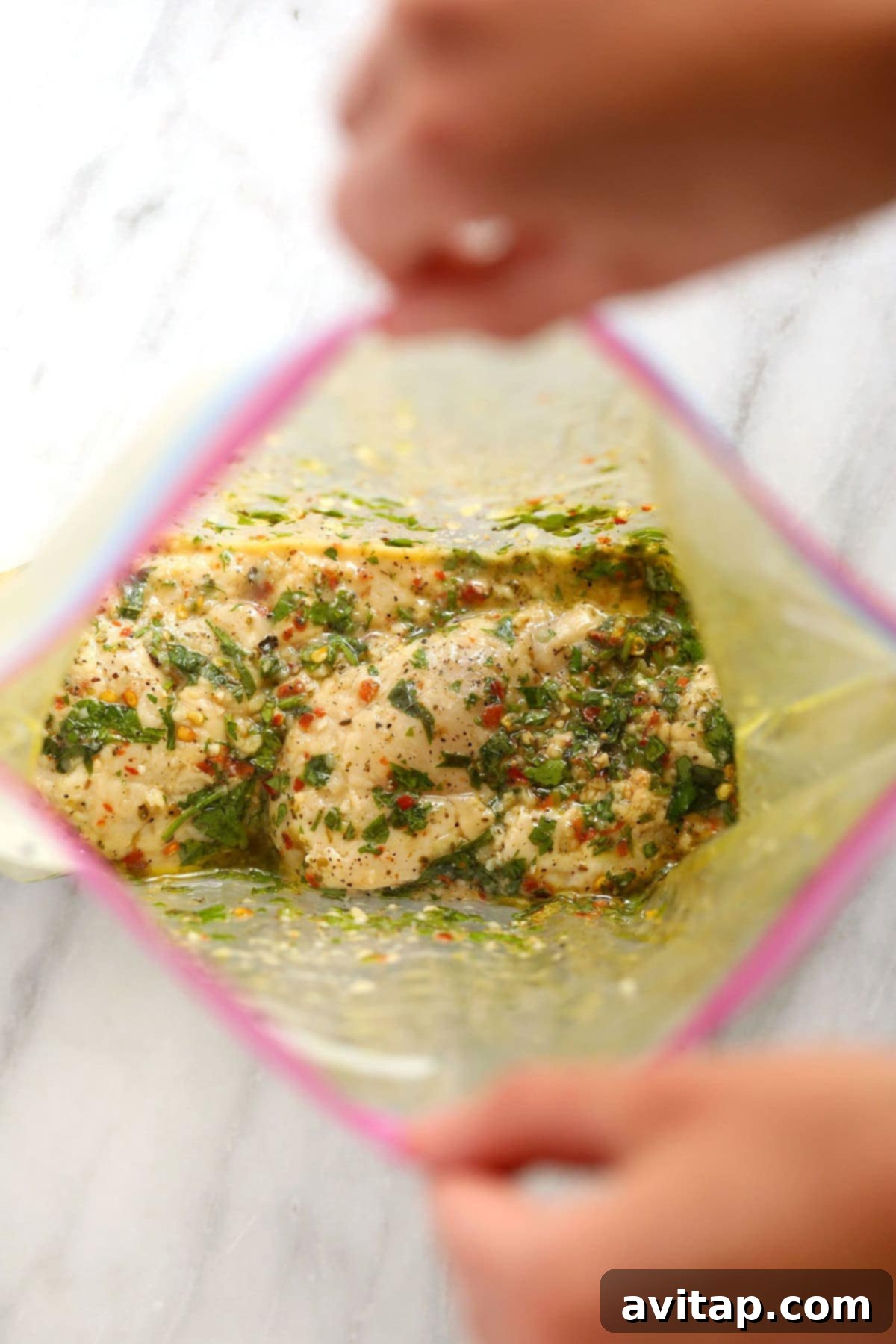 Chicken breasts marinating in an Italian dressing inside a freezer-safe plastic bag.