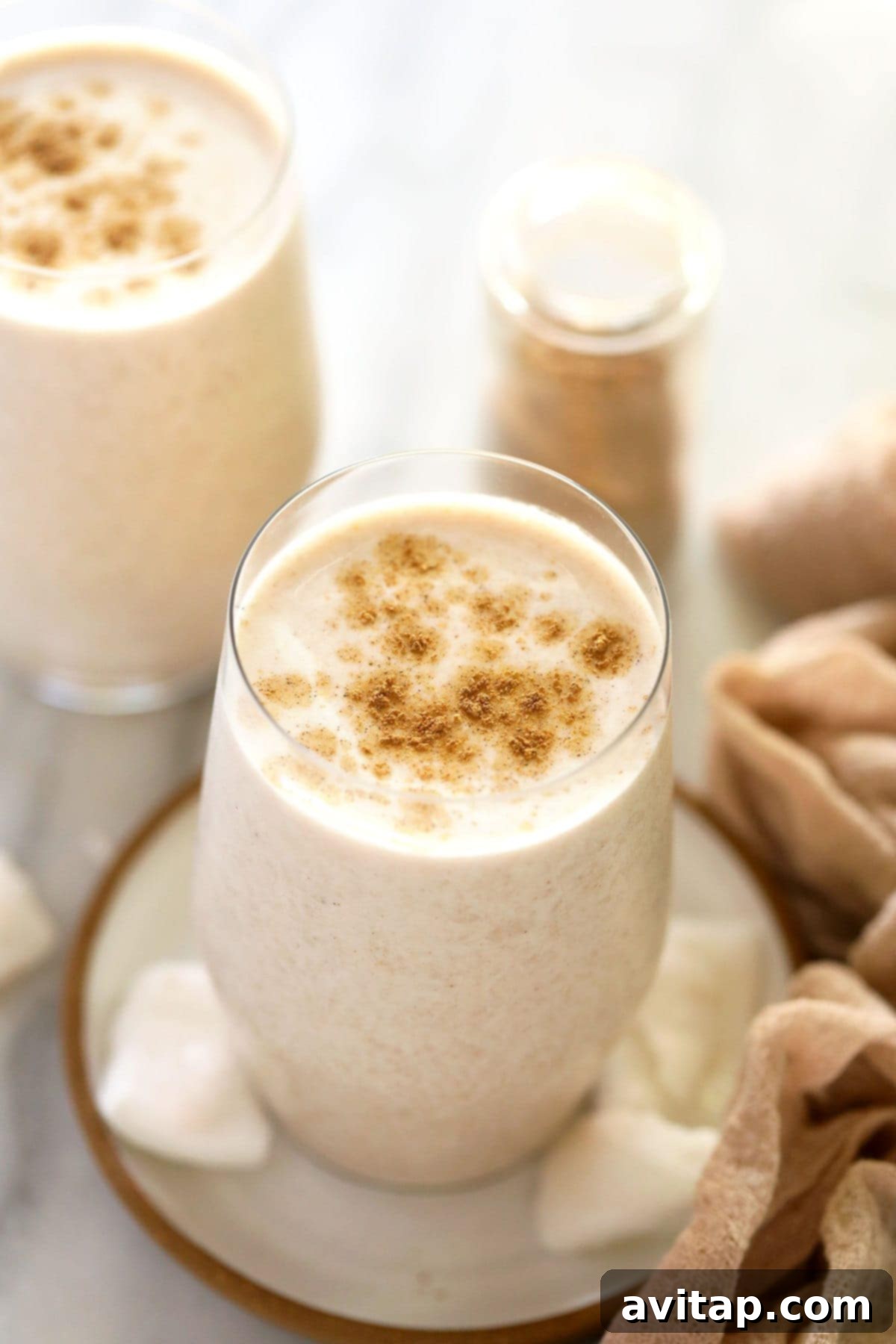Two glasses of creamy coconut chai protein shakes, garnished beautifully.