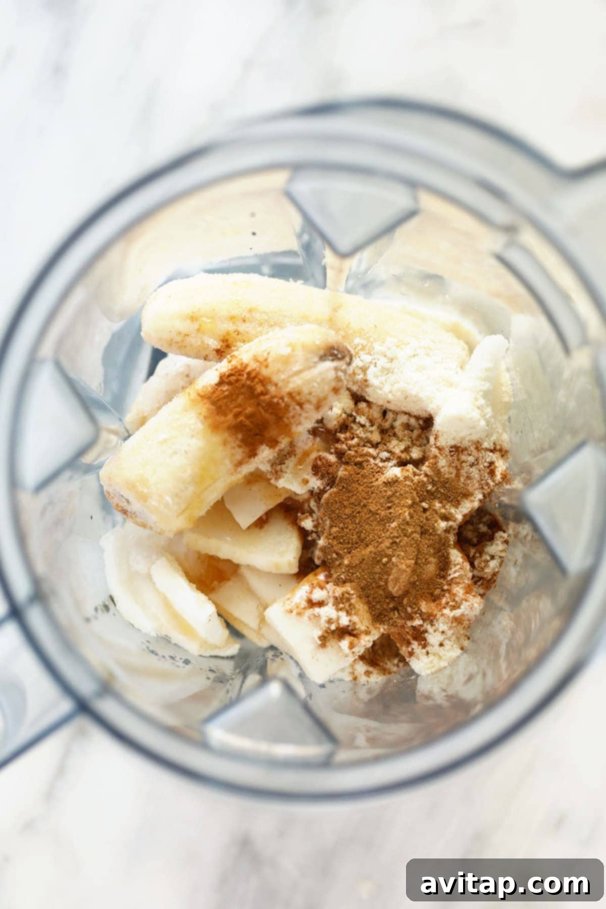 All the fresh ingredients for the chai protein shake displayed beautifully inside a blender before blending.