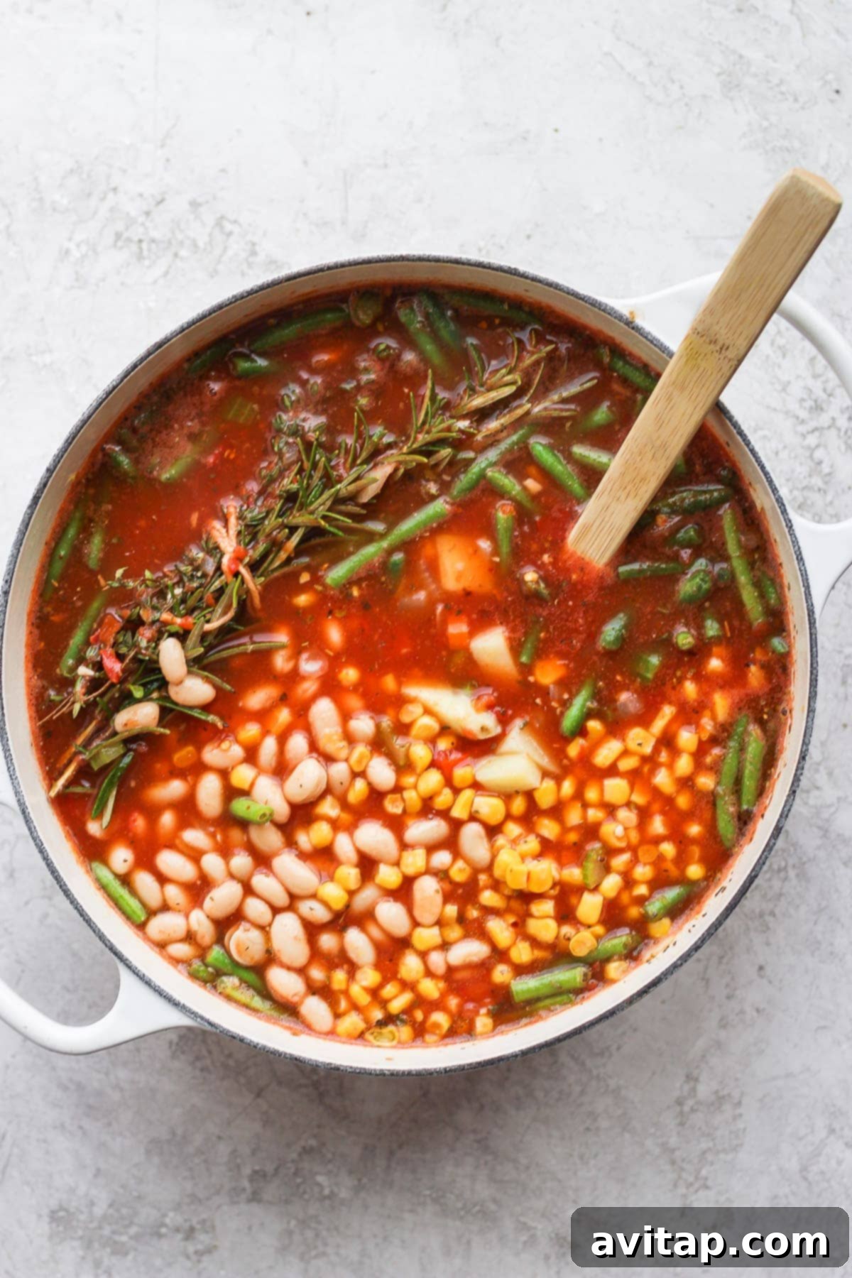 A steaming pot of hearty vegetable soup, brimming with colorful vegetables and a rich broth, ready to be served from a Dutch oven.