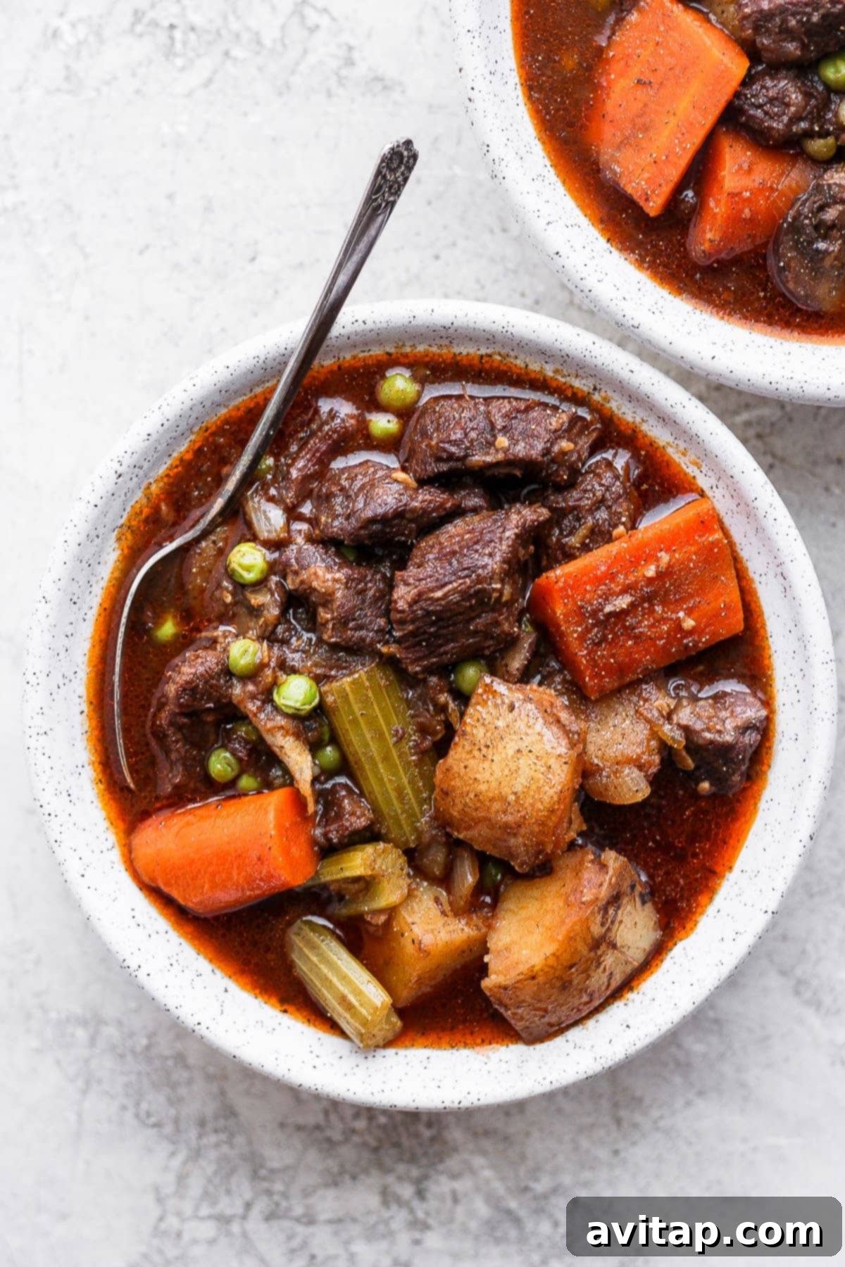 A steaming bowl of Instant Pot Beef Stew, rich with tender beef and vibrant vegetables, with a spoon nestled inside.