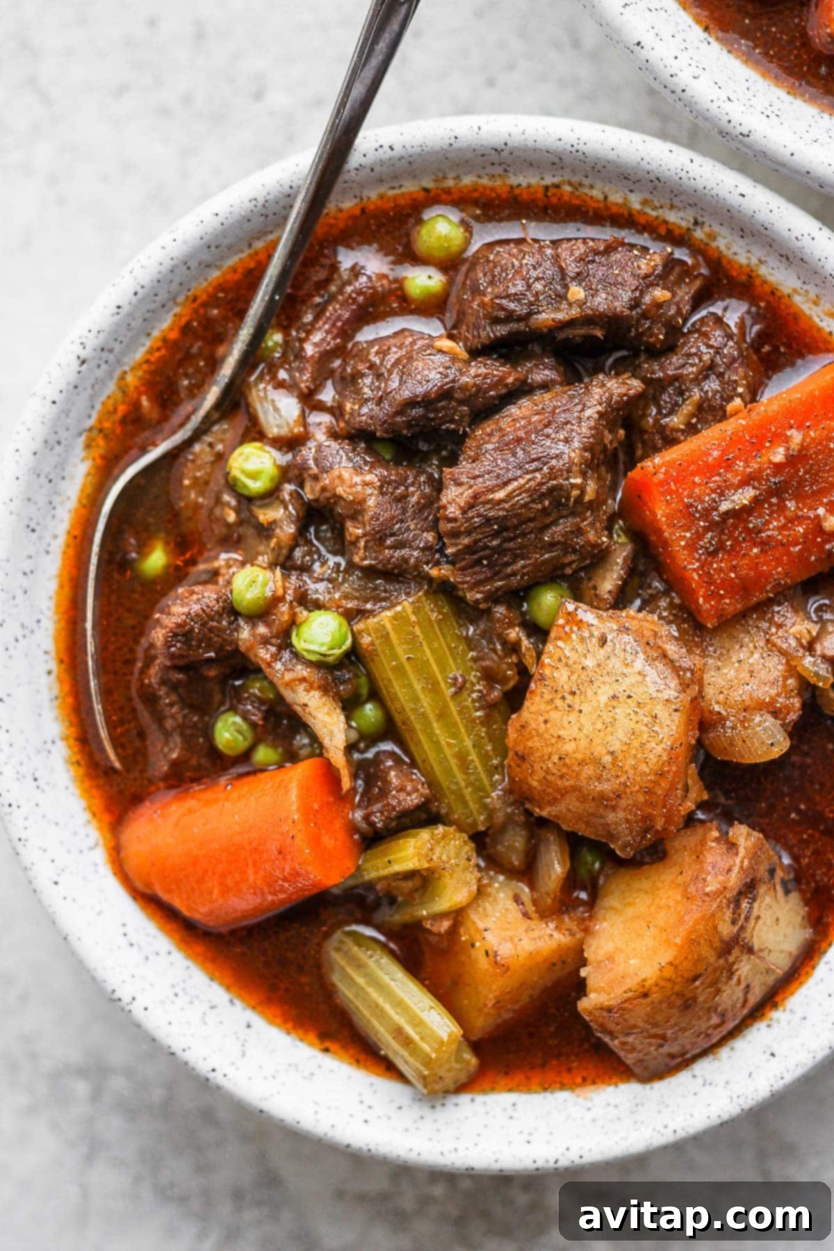 A generous bowl of steaming Instant Pot beef stew, garnished with fresh herbs, with a spoon ready to dive in.