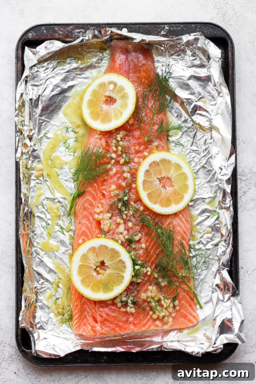 A full salmon fillet marinating in a vibrant lemon dill sauce