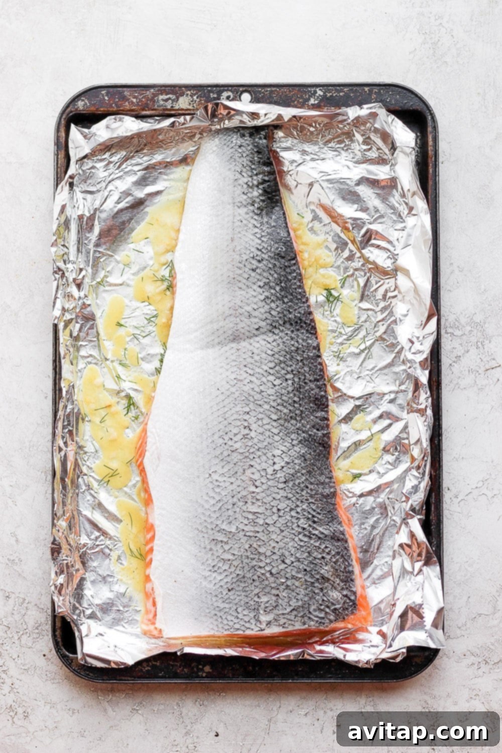 Salmon marinating in a baking sheet with foil
