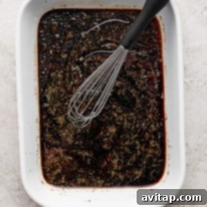 A bowl of brown liquid with a whisk, showing the marinade ingredients being combined.