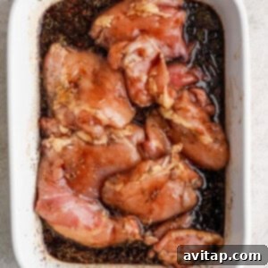 Marinating chicken breasts in a white baking dish in the refrigerator.