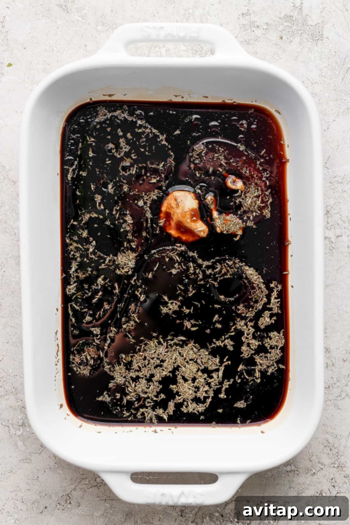 A pristine white baking dish showcasing a rich, brown balsamic sauce.