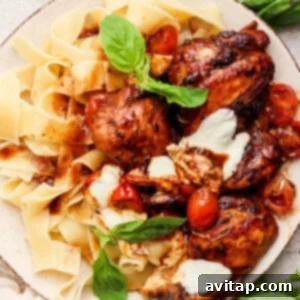 Grilled chicken with pasta and tomatoes on a plate, showcasing a complete meal.