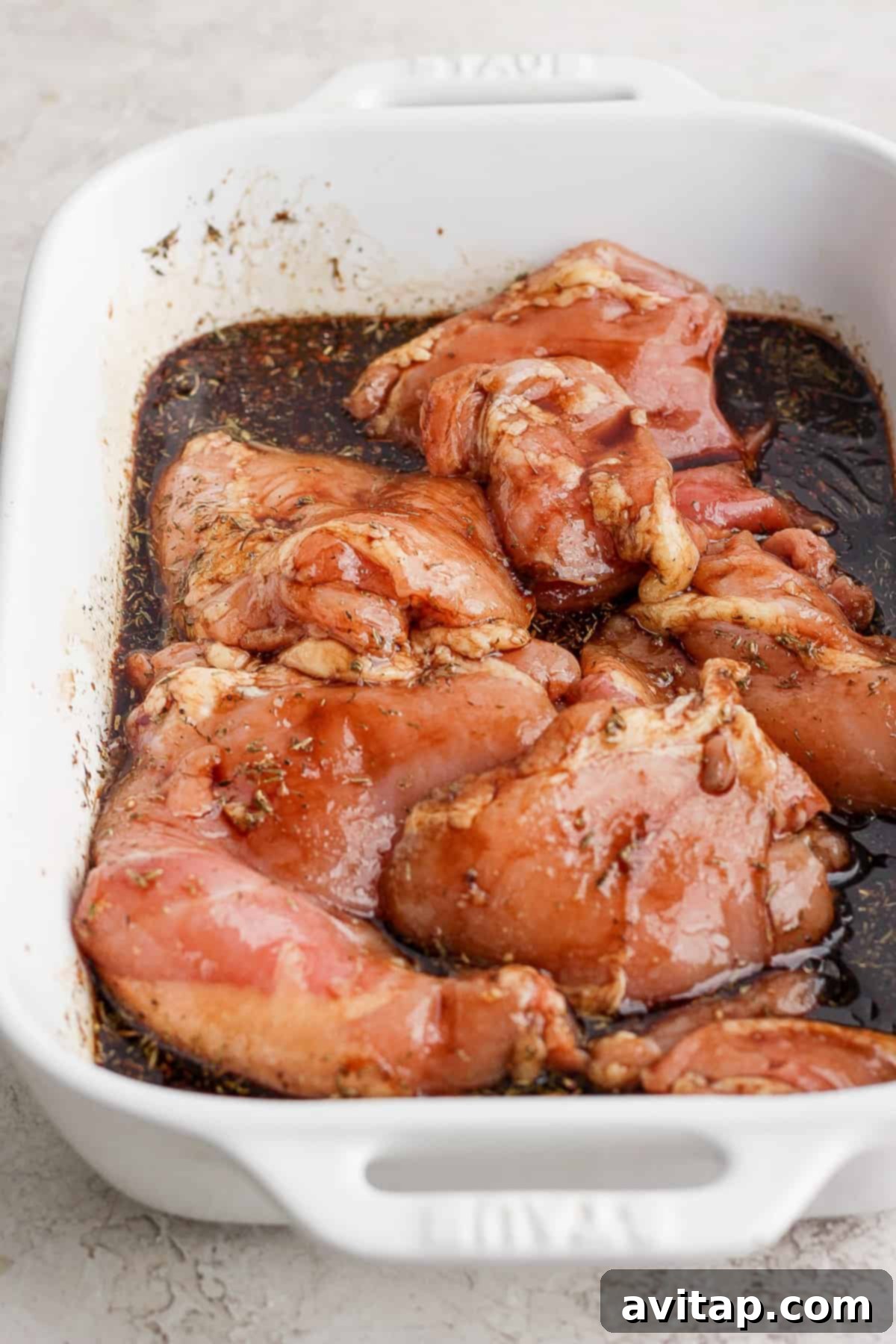Cooked chicken breasts in a white baking dish, glistening with a savory balsamic sauce.
