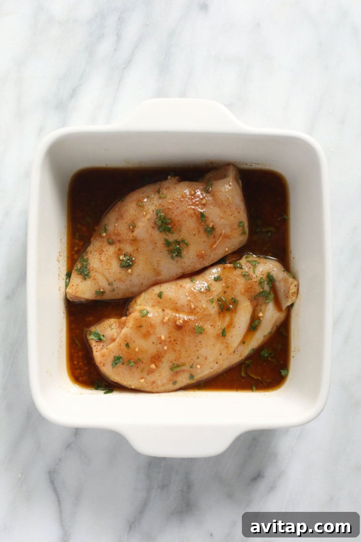 Chicken marinating in a casserole dish, ready for baking.