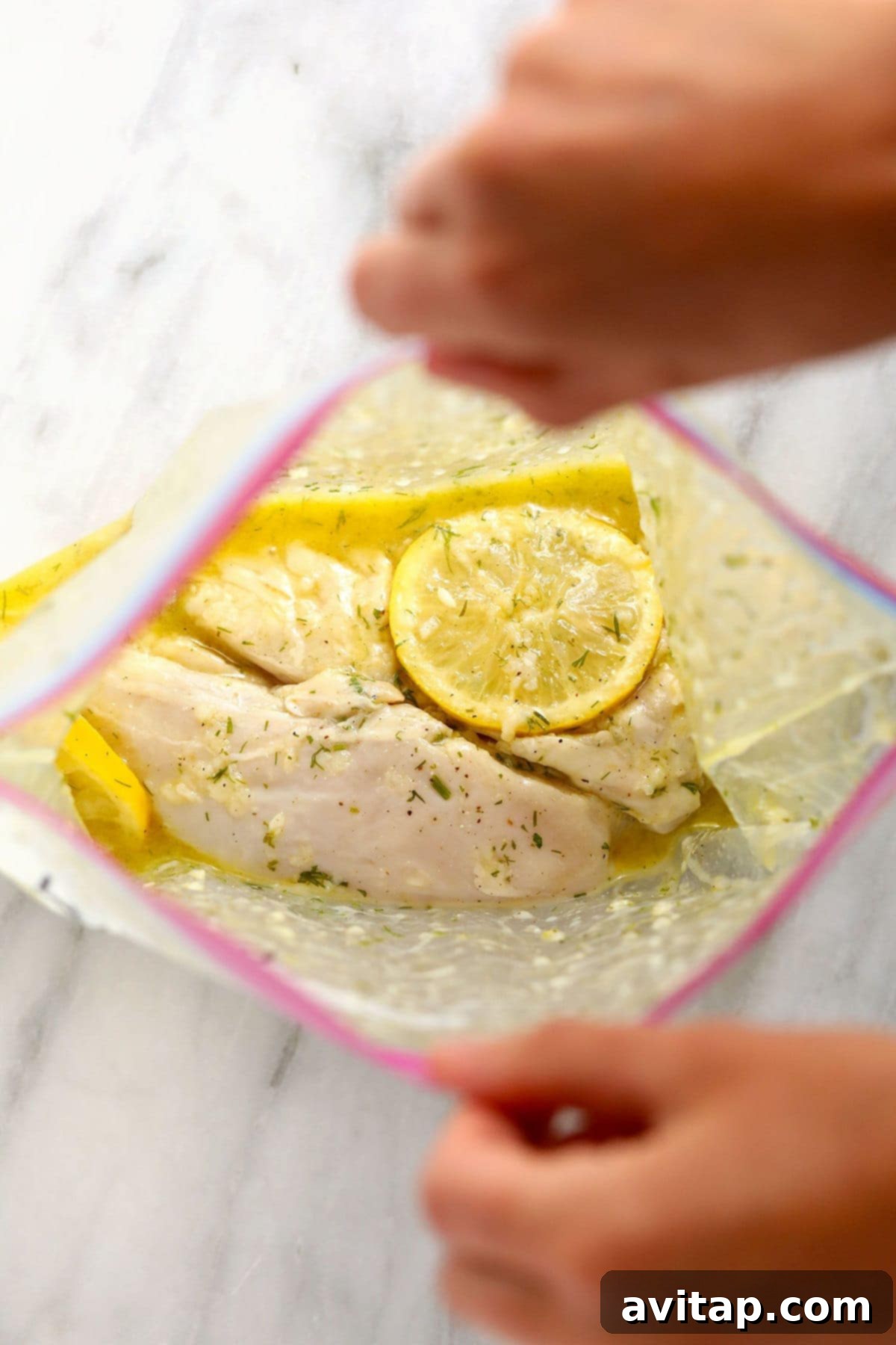 Lemon chicken marinating in a clear gallon-size freezer bag, ideal for convenient storage and flavor infusion.