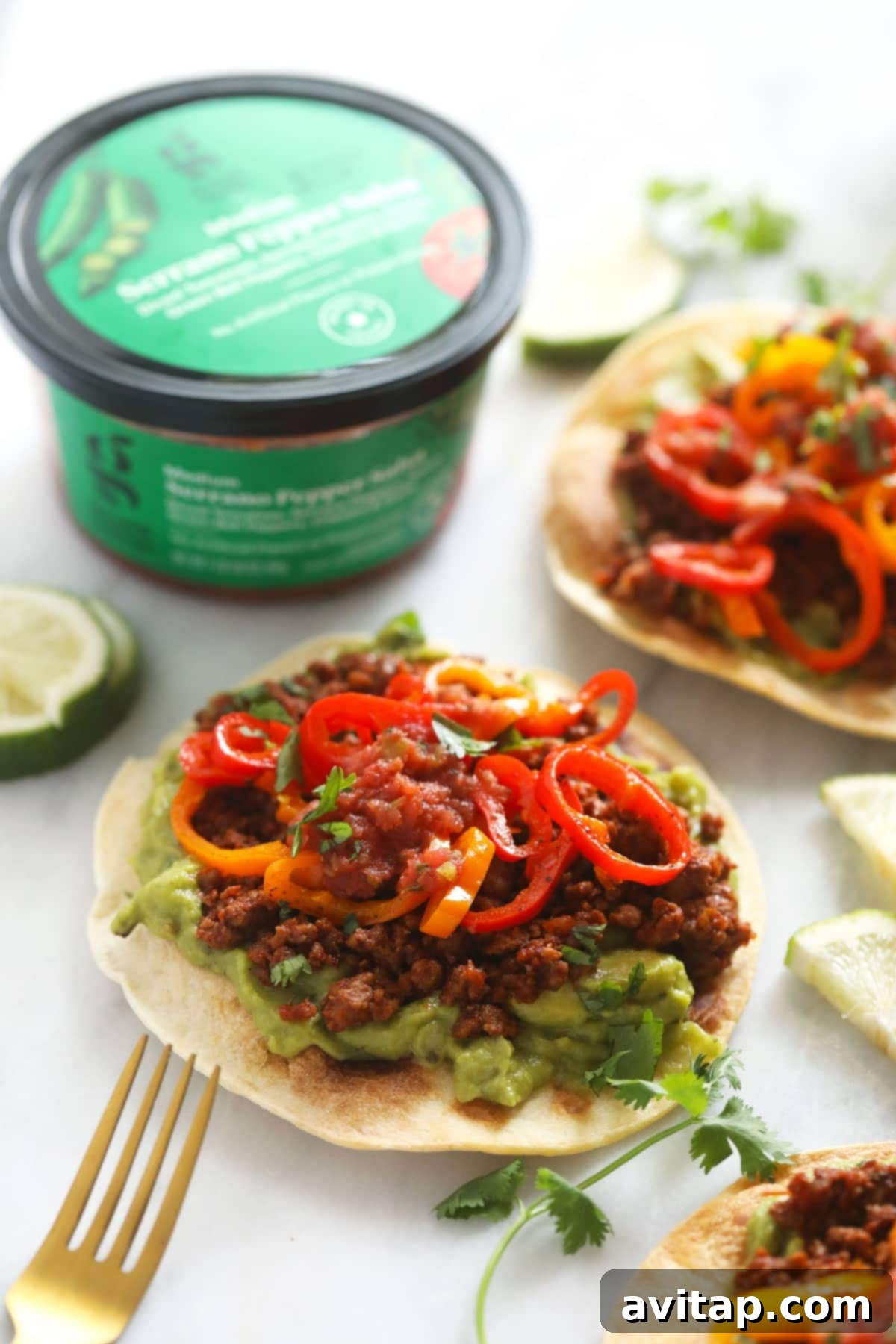 Crispy vegetarian tostada topped with creamy guacamole, savory plant-based ground, and fresh mini sweet peppers