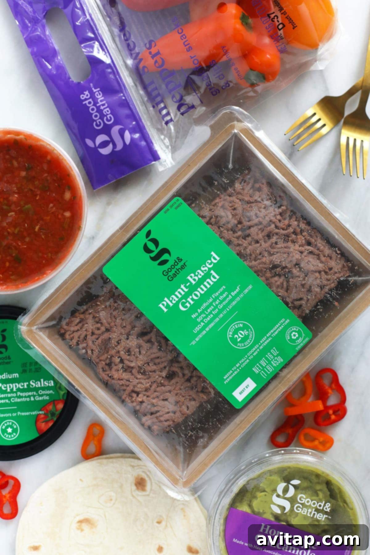 Collection of fresh ingredients for vegetarian tostadas: plant-based ground, creamy guacamole, corn tortillas, spicy salsa, and colorful mini sweet peppers