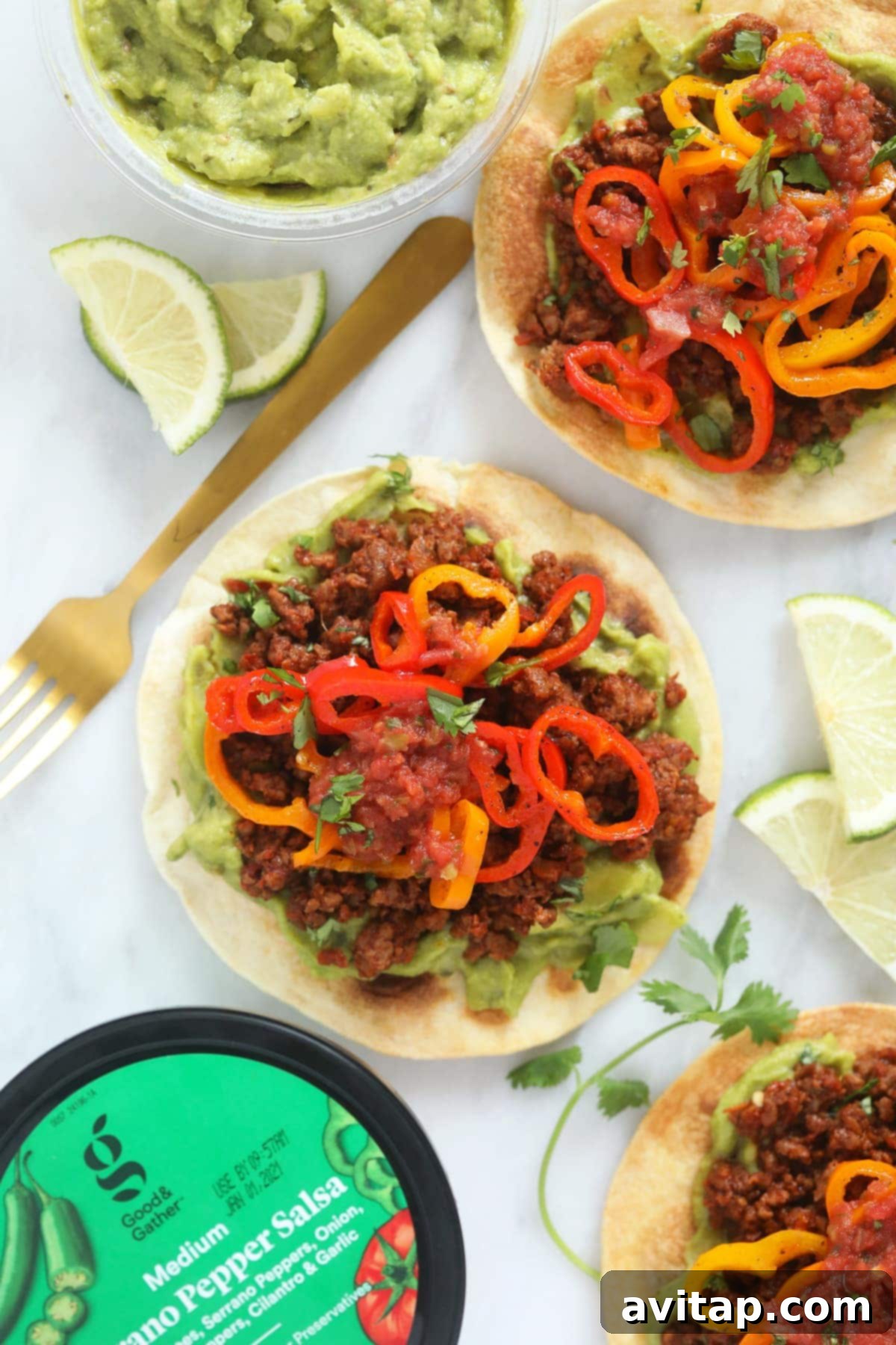 Vegetarian tostada garnished with fresh lime wedges and vibrant mini sweet peppers