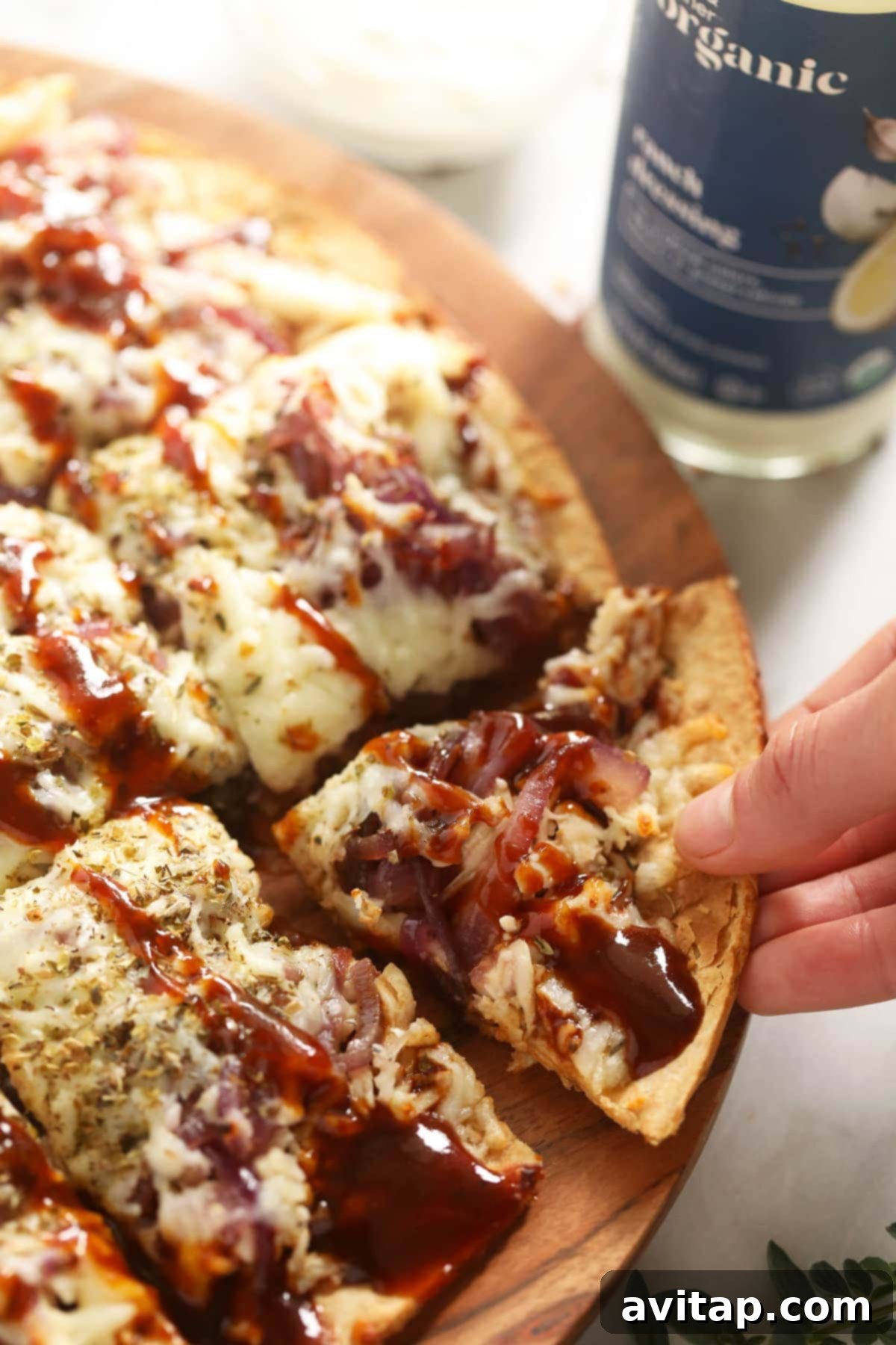 Close-up of a golden-brown BBQ chicken pizza slice, showing the generous sauce and toppings.