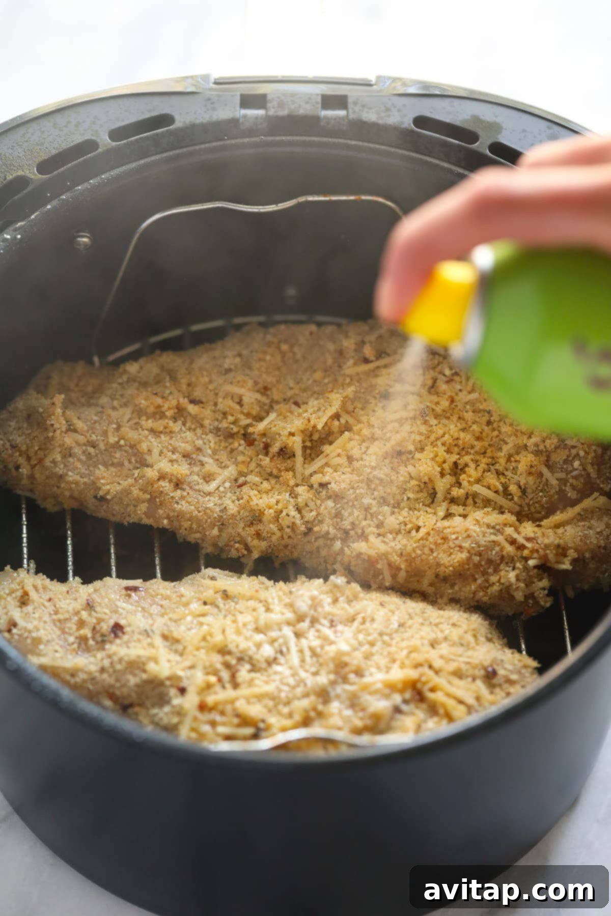 spraying chicken parmesan with cooking spray