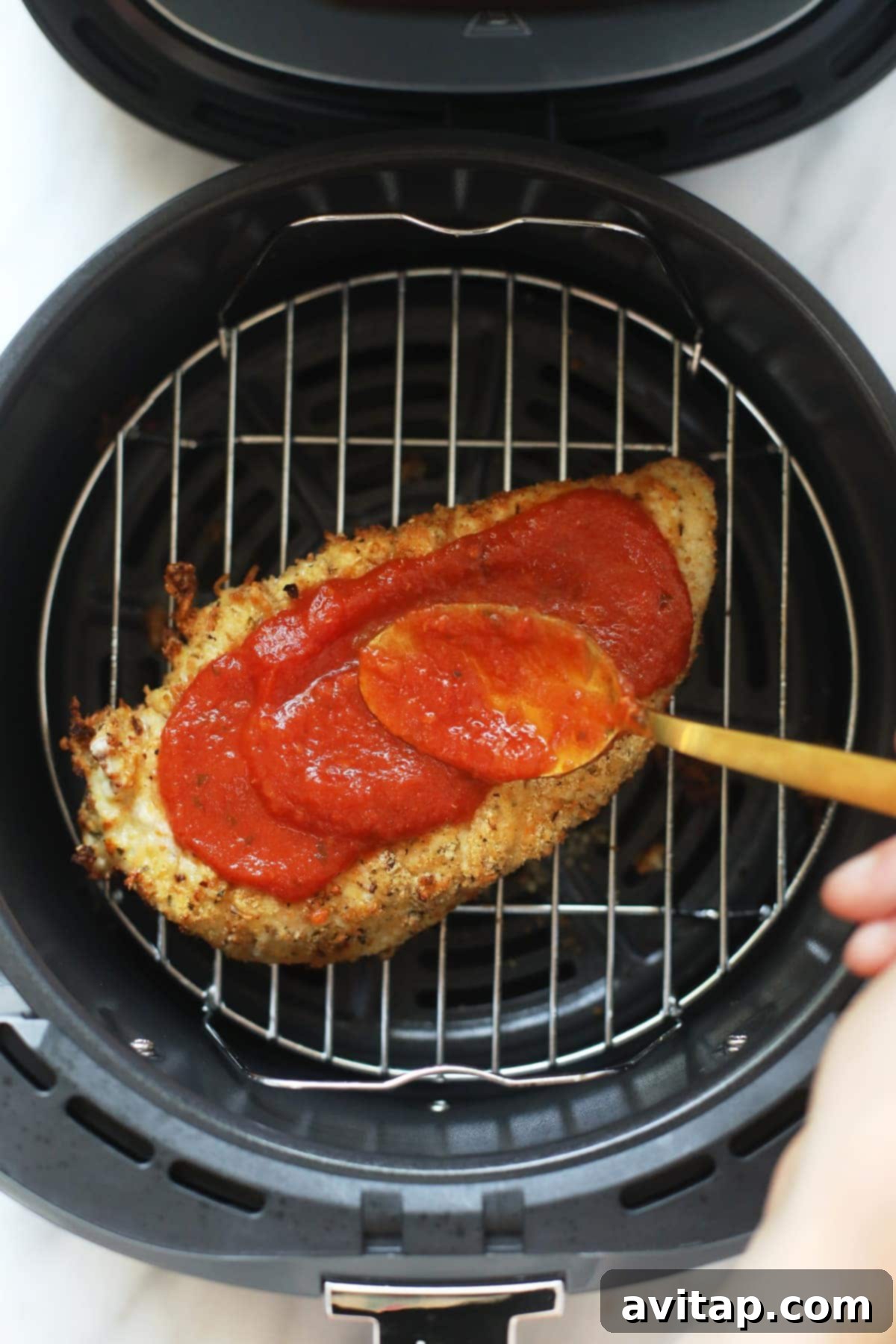 rubbing chicken parmesan with marinara sauce in air fryer