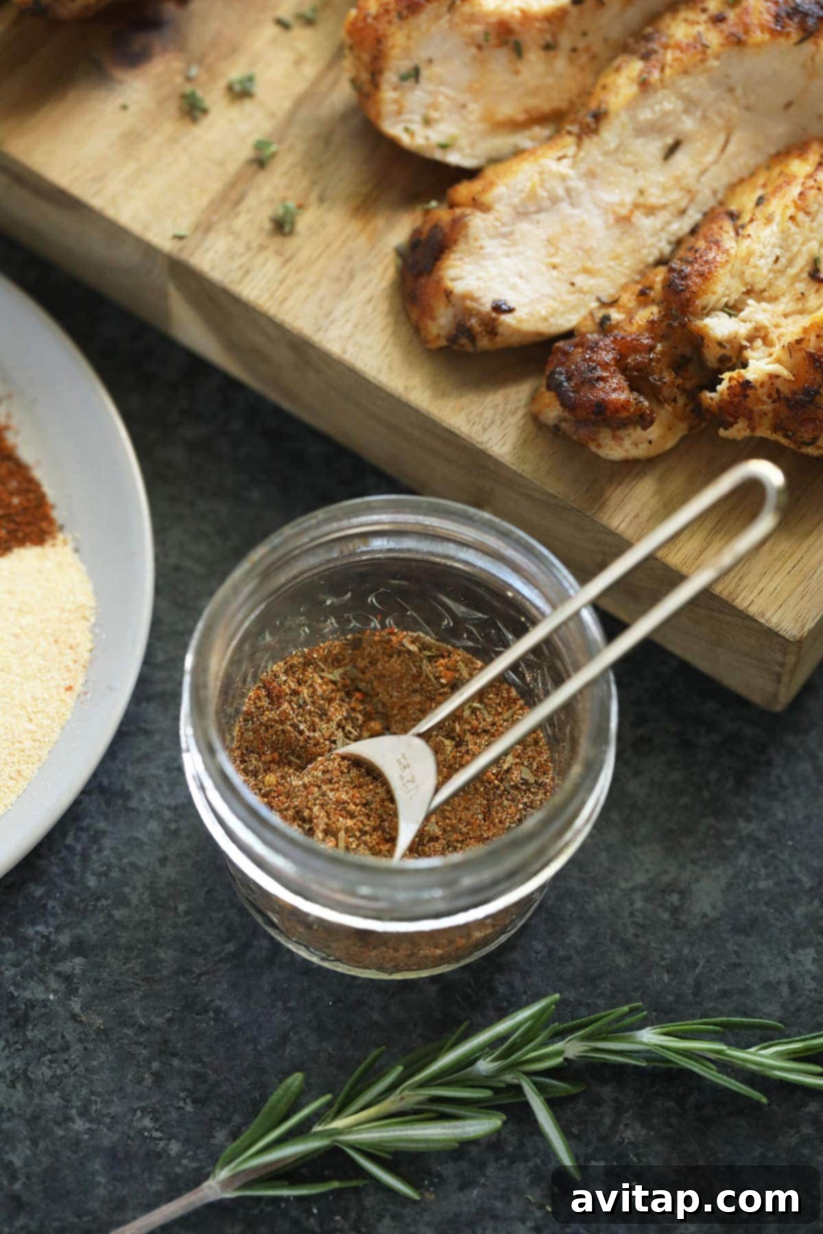 A small glass jar filled with the vibrant all-purpose chicken seasoning, sealed and ready for storage.