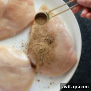A seasoned chicken breast resting on a plate, ready for cooking after absorbing the delicious rub.