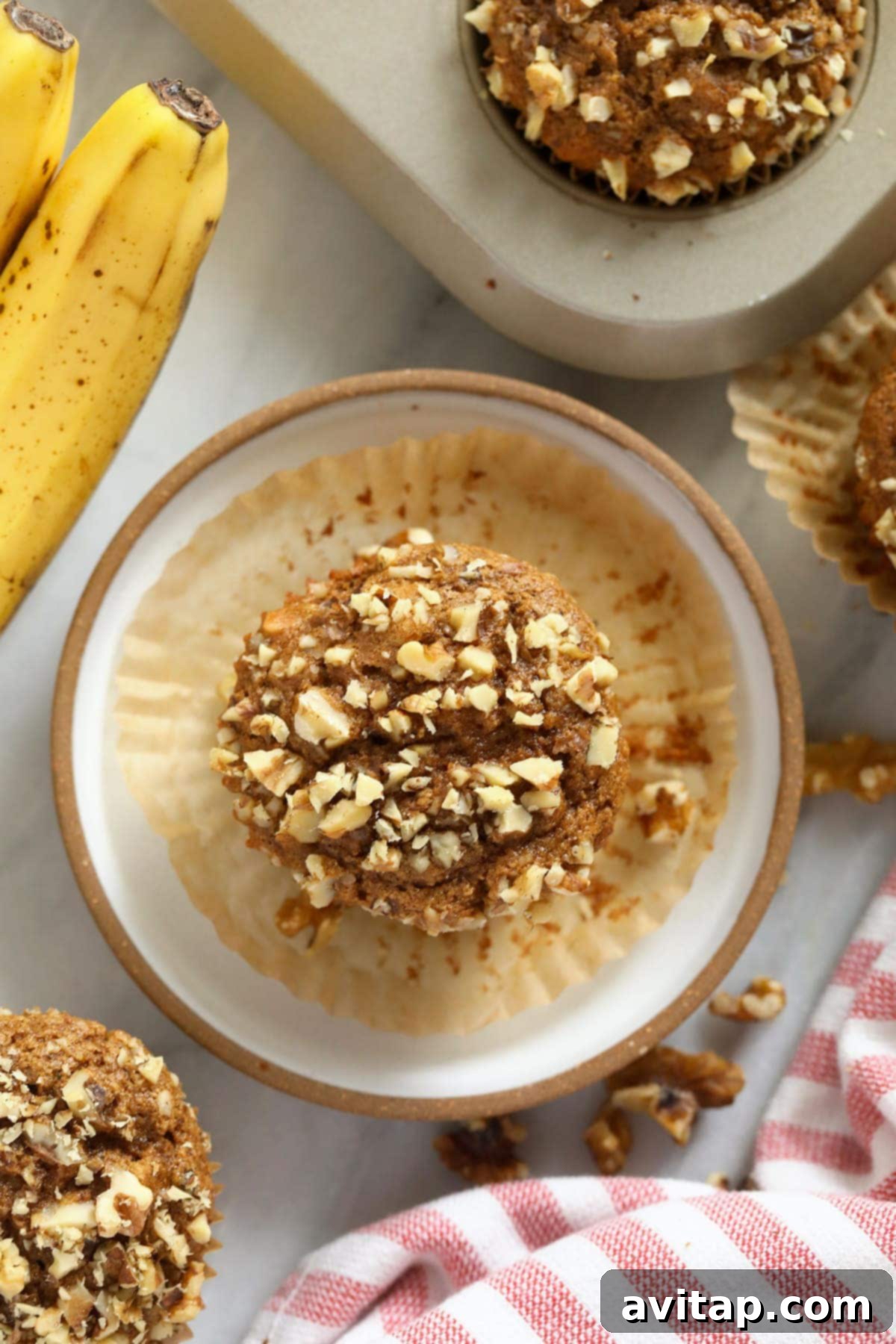 Deliciously baked banana nut muffins arranged beautifully on a white plate and in a muffin pan, showcasing their golden-brown, crunchy tops and inviting texture.