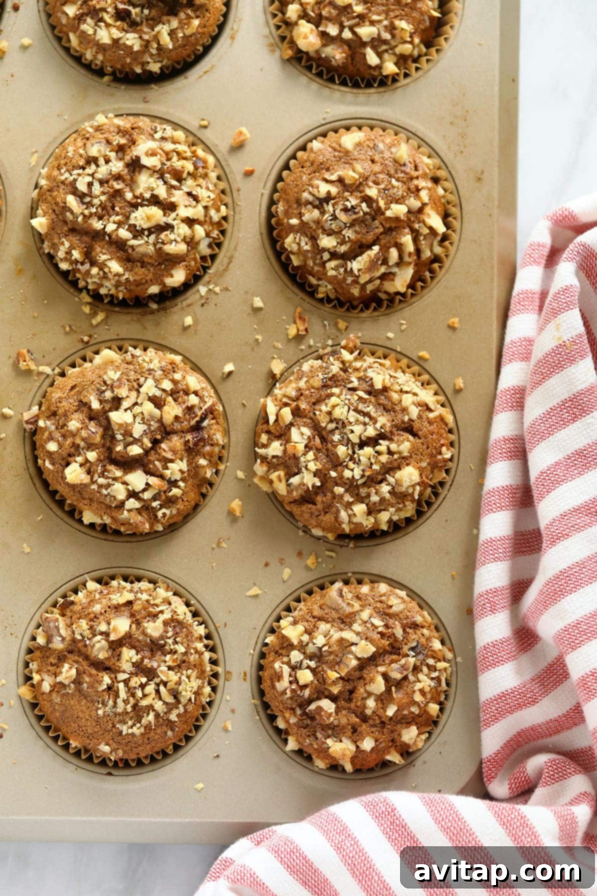 A close-up of golden-brown banana nut muffins with beautifully crunchy tops, cooling gently in a muffin tin, highlighting their perfect rise and inviting texture.