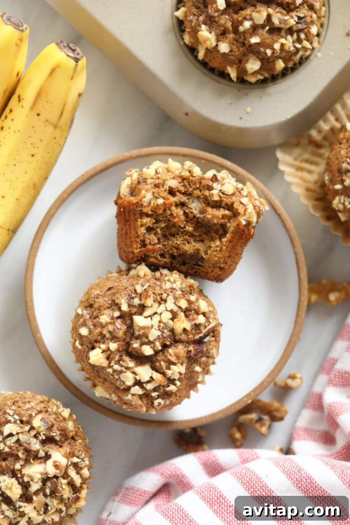 Two perfectly baked banana nut muffins sitting invitingly on a white plate, ready to be savored as a wholesome and delicious snack or breakfast item.