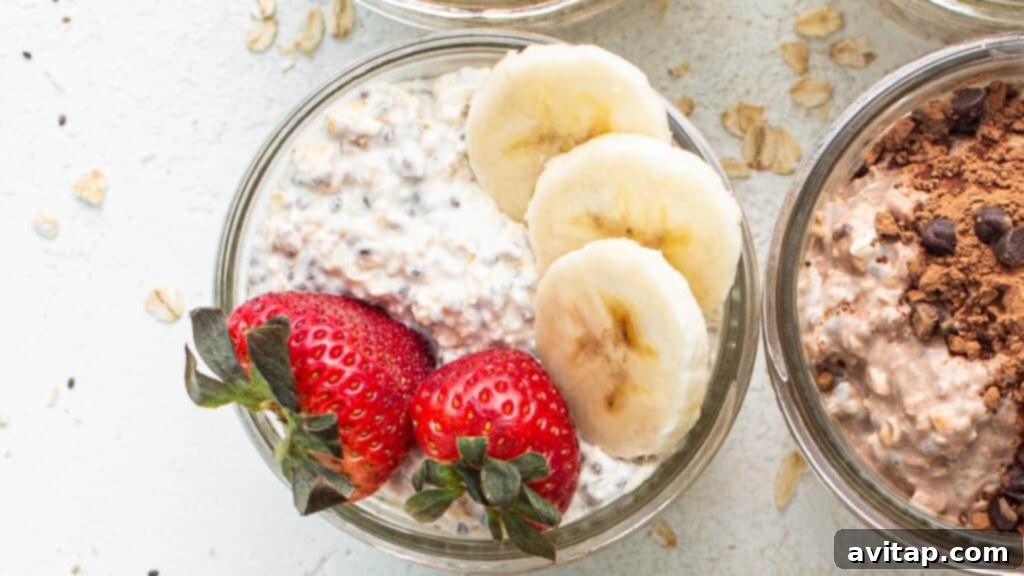 Three jars of strawberry banana overnight oats, decorated with fresh strawberry slices, banana pieces, and chocolate chips.