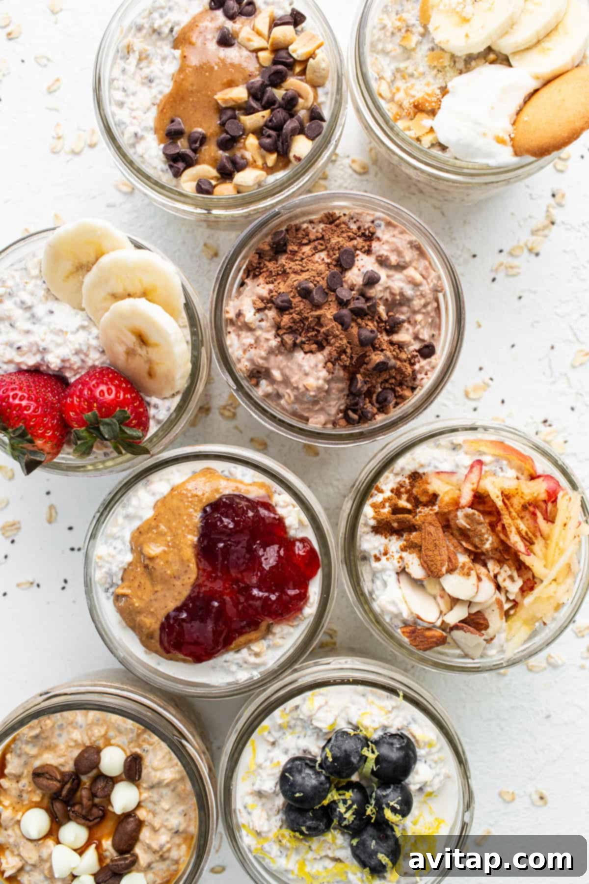 A display of various jars filled with colorful overnight oats, garnished with fresh fruits, nuts, and other enticing toppings.
