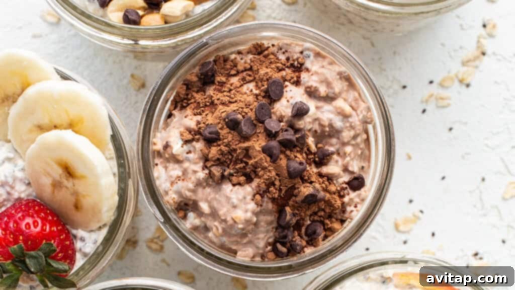Jars of chocolate protein overnight oats, topped with banana slices, strawberries, and mini chocolate chips.