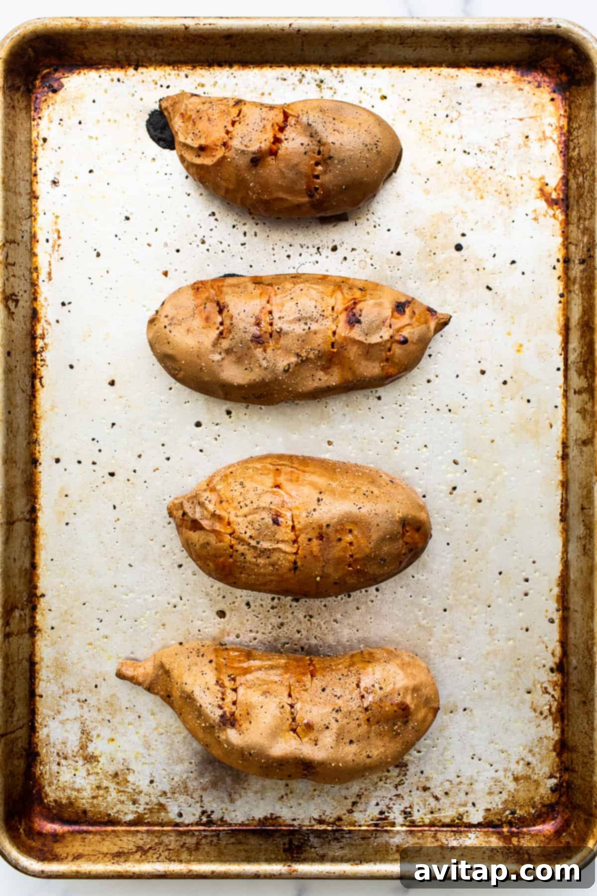 Baked sweet potatoes on a baking sheet, fresh out of the oven.
