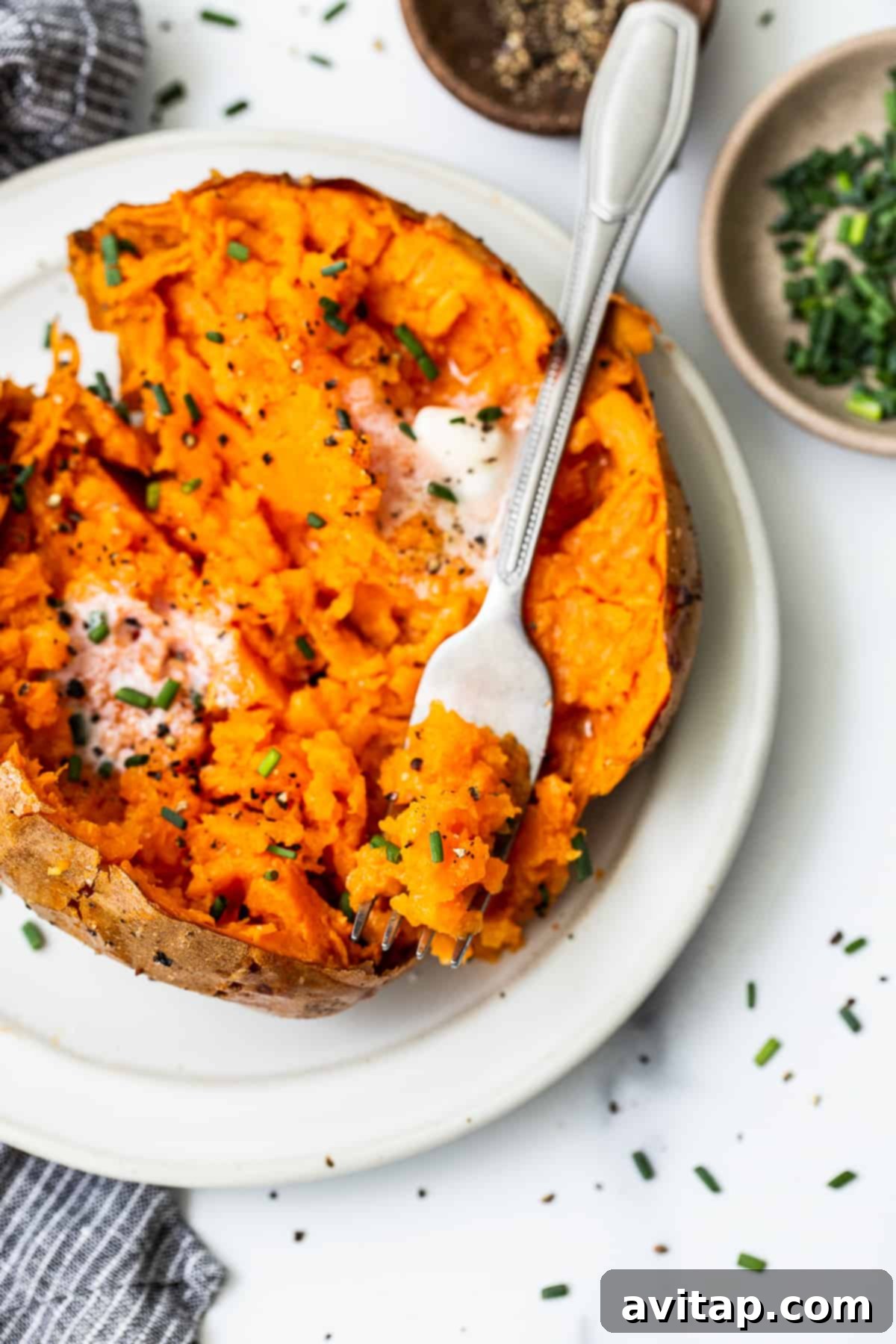 Baked sweet potato on a fork, showing its fluffy interior.
