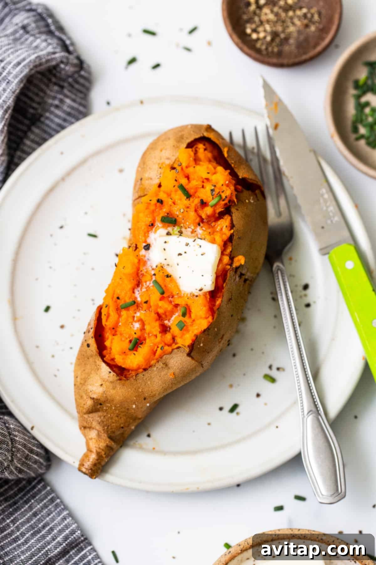 Baked sweet potato on a plate topped with butter.