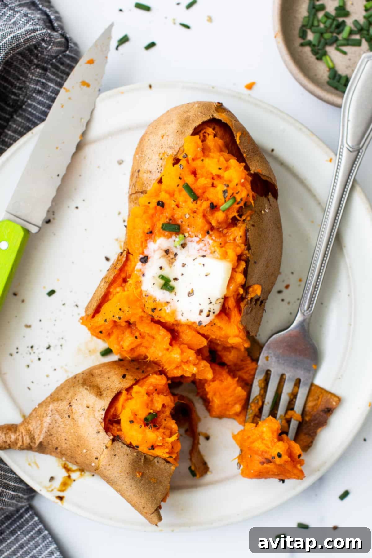 Baked sweet potato on a plate with a fork.