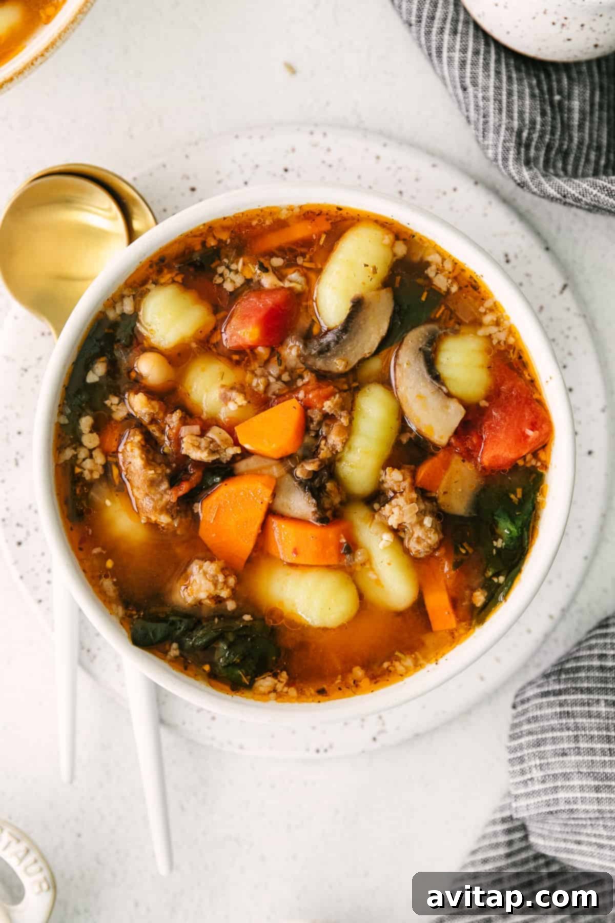 A steaming bowl of hearty one-pot sausage gnocchi soup, garnished with fresh herbs, ready to be enjoyed as a perfect weeknight comfort food.