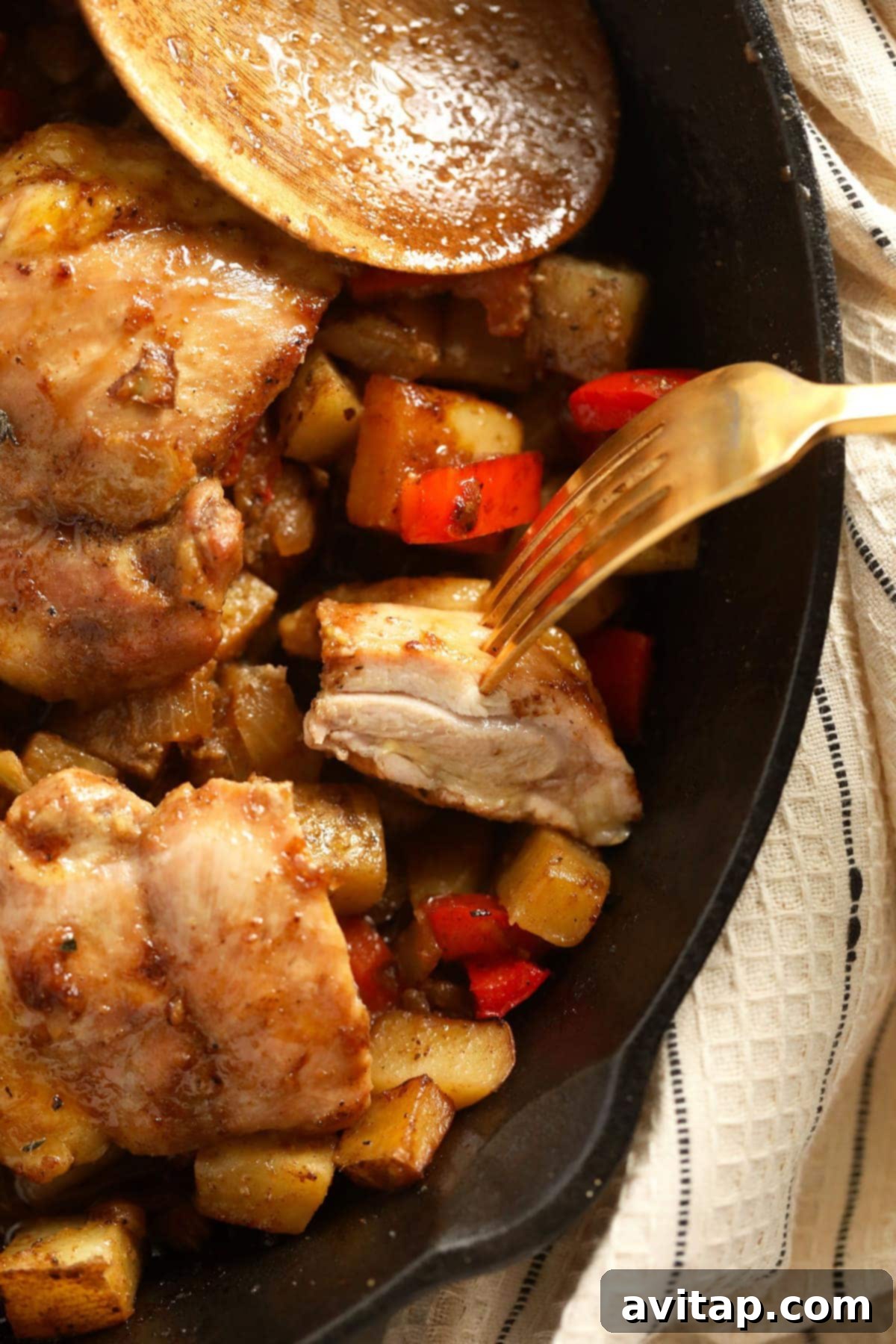 A fork holding a juicy, perfectly cooked bite of seasoned chicken thigh, highlighting its tender texture