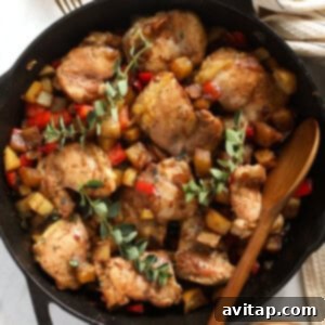 A top-down view of skillet chicken and potatoes, perfectly browned and garnished in a cast iron skillet