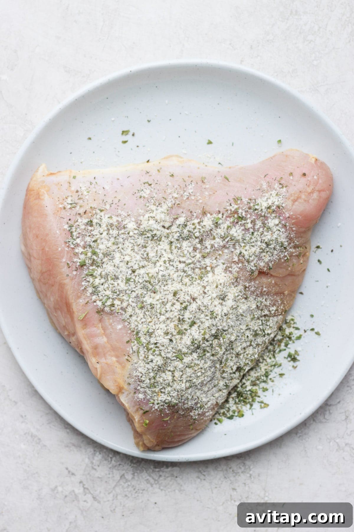 Raw turkey breast generously coated with a savory ranch dry rub, ready for the oven.