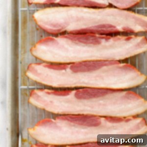 Bacon strips on a baking sheet, ready for partial cooking.